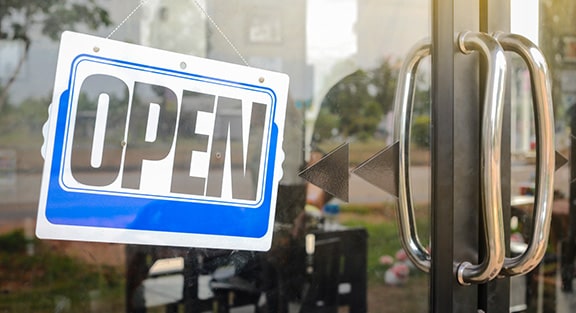 Blue and white open sign displayed on glass door of pool and spa contractor storefront