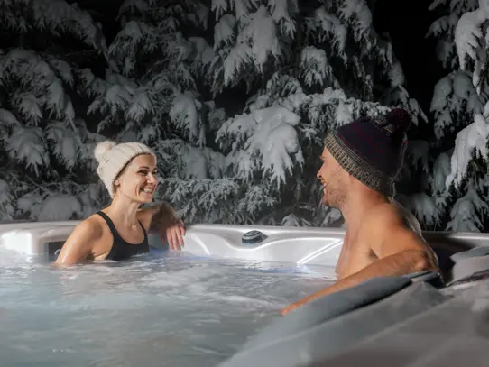 Outdoor hot tub used in winter with couple relaxing in warm water