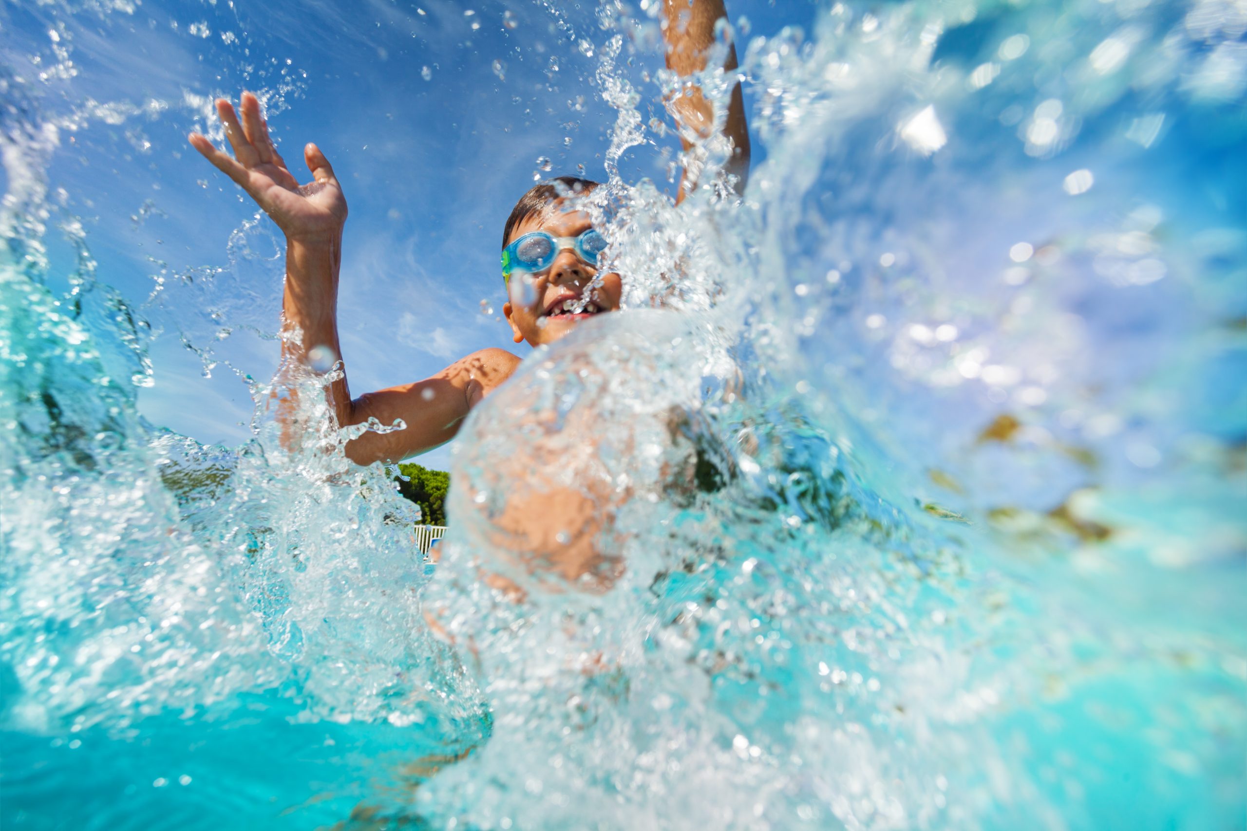 Child enjoying summer fun swimming in above ground pool with goggles