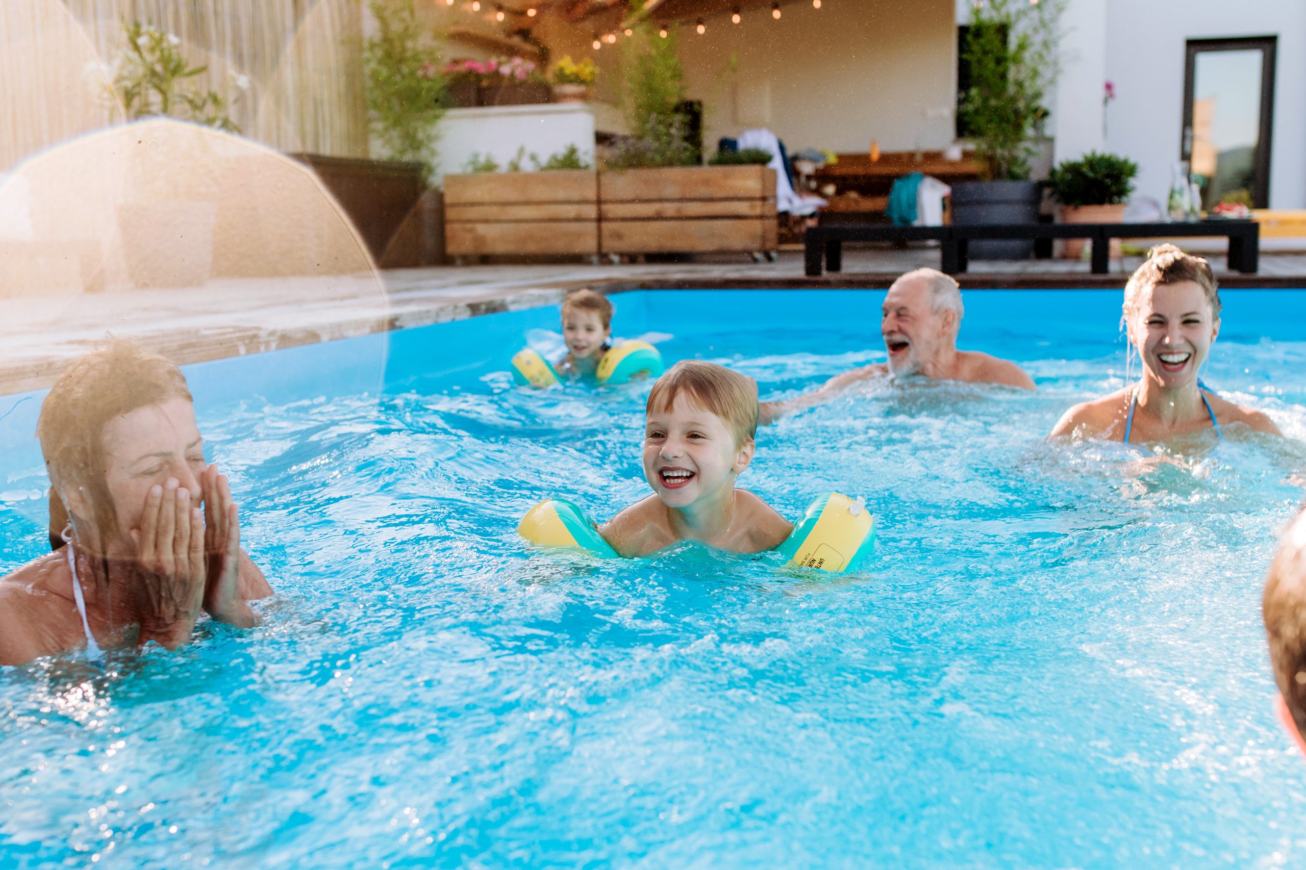 Family enjoying above-ground pool with children wearing yellow floaties