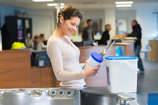 Woman holding pool maintenance chemicals and supplies in modern showroom