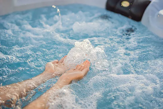 Person enjoying bubbling jets in a hot tub with spa installation features visible
