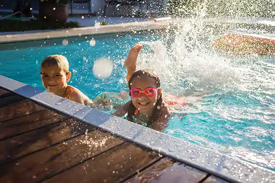 Children enjoying a sunny day swimming in an above ground pool with accessories
