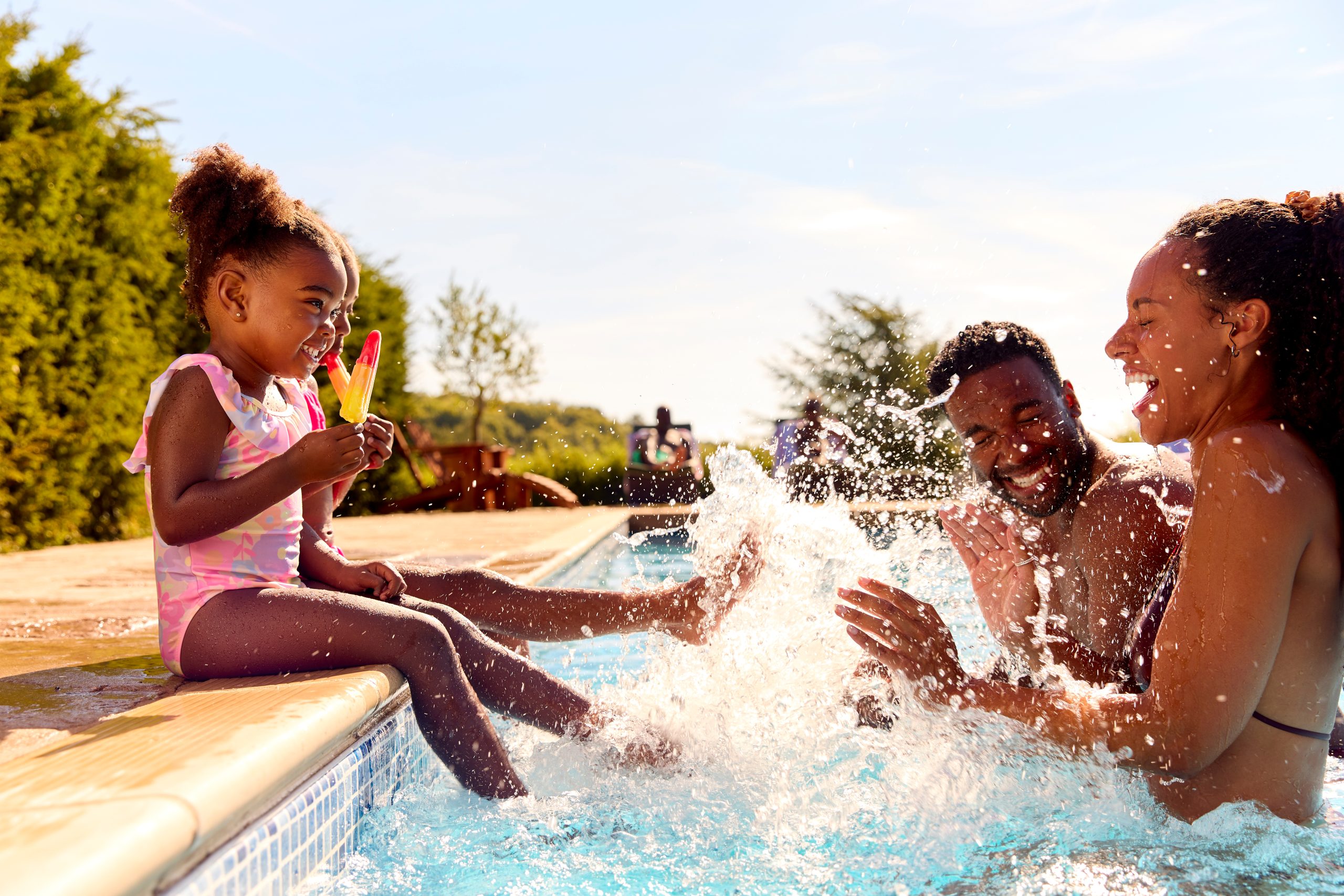 Family enjoying summer fun in backyard above ground pool with water splashing