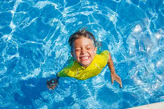 Happy child enjoying an above ground pool with yellow floaties