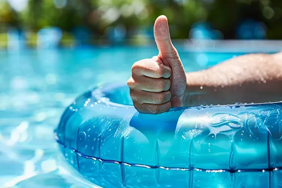 Person giving thumbs up while floating on blue pool float in above ground pool