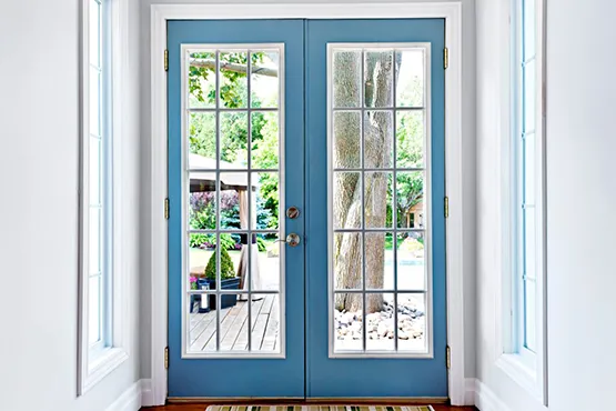 Blue French doors with glass panes opening to outdoor patio area