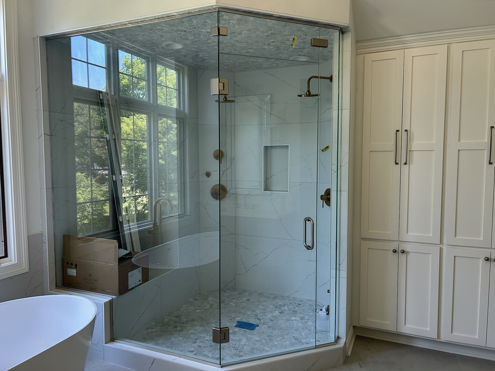 Luxury glass shower installation featuring frameless enclosure and marble tile in modern bathroom